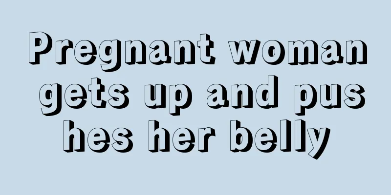 Pregnant woman gets up and pushes her belly